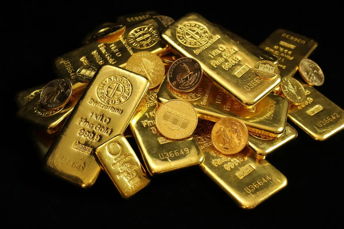 Moedas e barras de ouro sobre fundo preto