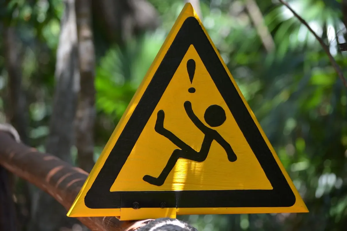 Placa amarela de aviso em meio à vegetação
