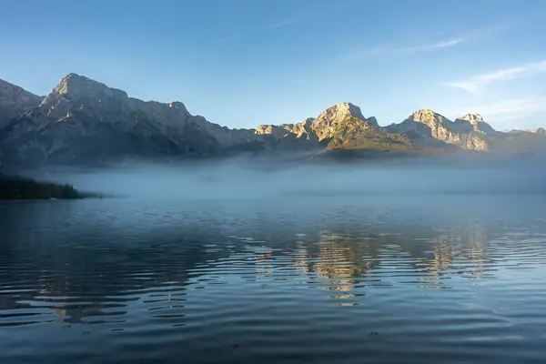 Lago de montanha com neblina ao amanhecer