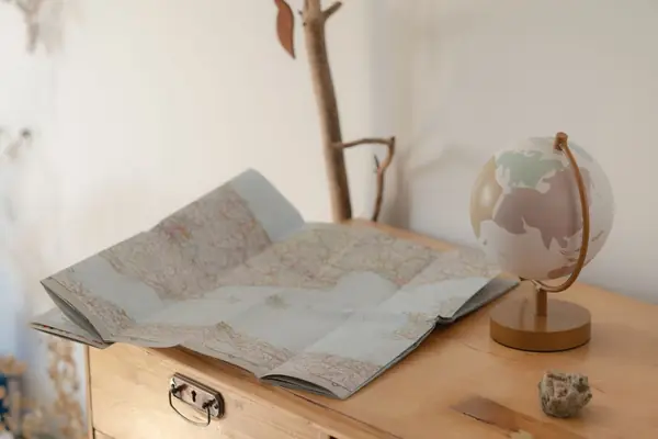 Mapa aberto sobre uma mesa ao lado de um globo
